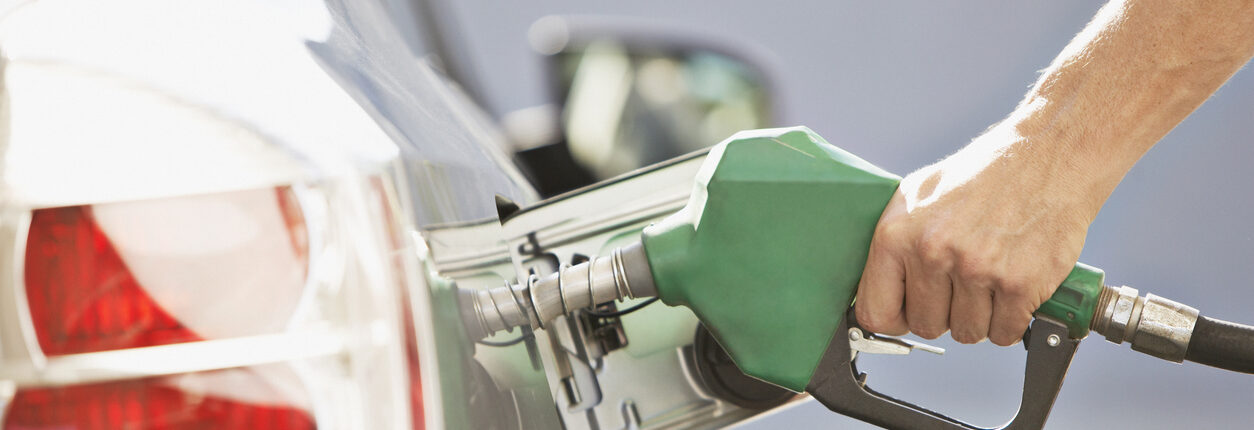 Une personne qui remplie son réservoir de carburant avec un pistolet vert