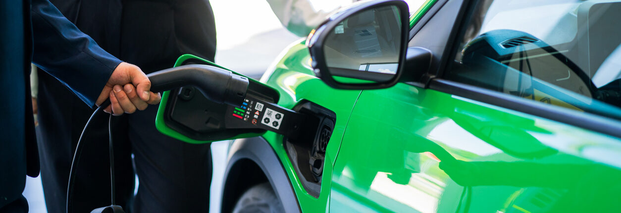 une voiture verte qui se recharge à la borne électrique