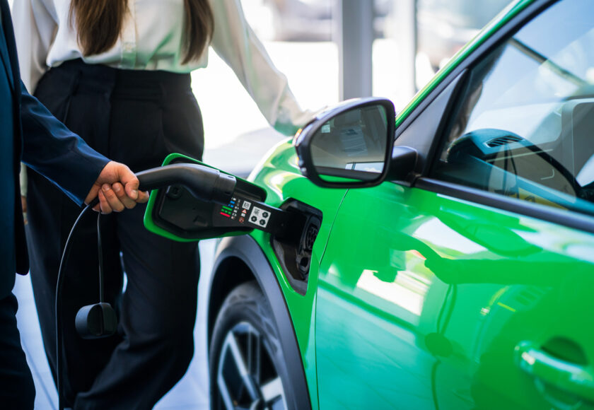 une voiture verte qui se recharge à la borne électrique