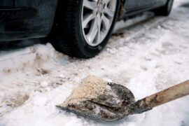 Pelle avec du sel sur une allée enneigée pour éviter les glissades. Application de sel de déneigement (salage) sur une route verglacée pour assurer la sécurité du trafic automobile. Espace libre pour le texte.