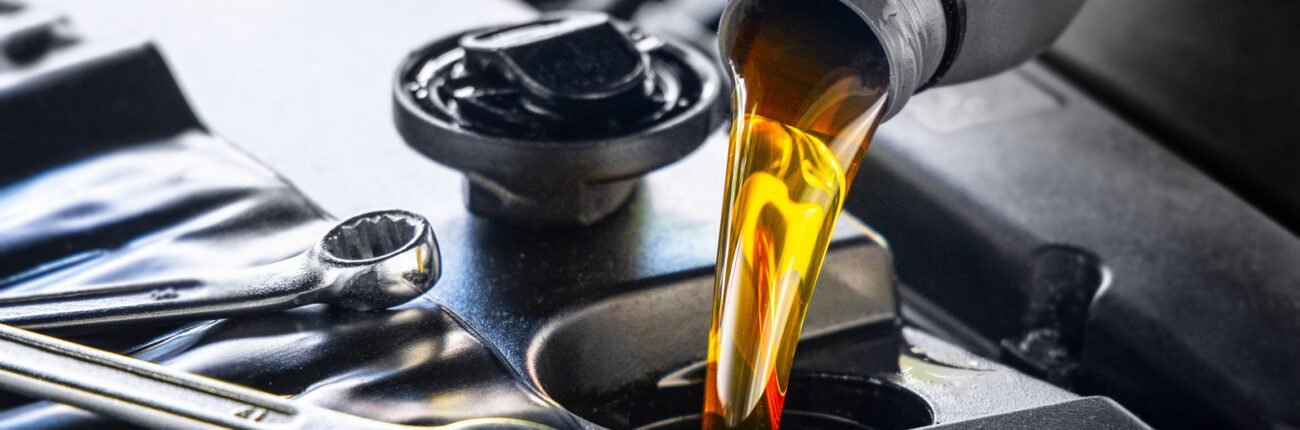 Versement d’huile moteur pour véhicules automobiles depuis un bidon gris dans le moteur, vidange, atelier de réparation automobile, entretien.