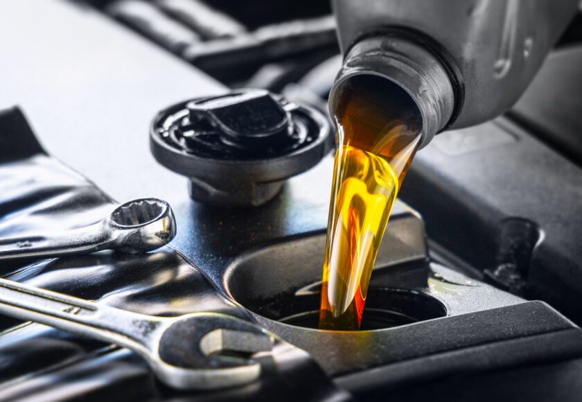 Versement d’huile moteur pour véhicules automobiles depuis un bidon gris dans le moteur, vidange, atelier de réparation automobile, entretien.