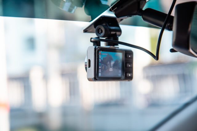 Caméra vidéo embarquée fixée au pare-brise pour enregistrer la conduite et prévenir les dangers sur la route.