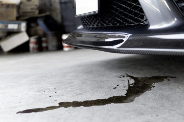 Taches d’huile moteur sous la voiture garée sur la route – photo illustrant un concept de service, de vérification et d’entretien.