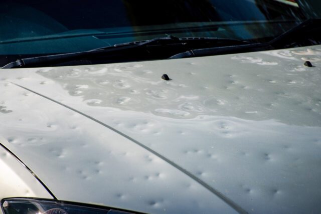 Capot de voiture endommagé par une forte tempête de grêle. Réparation des bosses par l'assurance auto. Capot de voiture cabossé après des intempéries.









