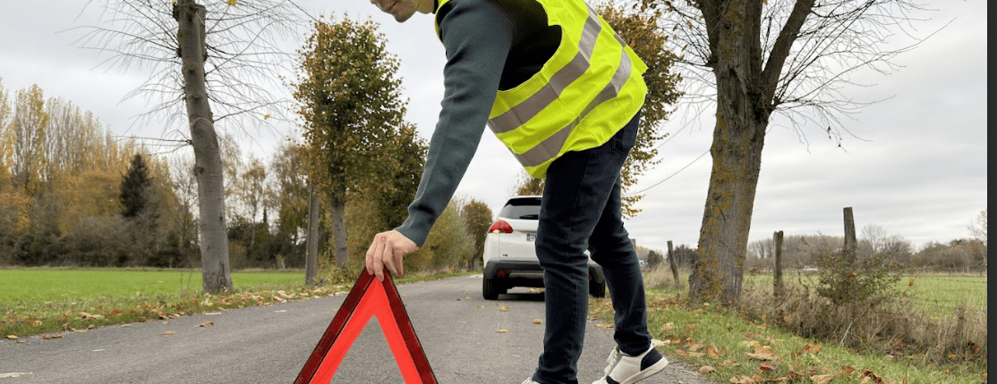 Un homme venant d'avoir un accident, pose son triangle de présignalisation vêtit de son gilet jaune de sécurité
