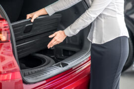 femme qui montre sa solution pour éviter de rester bloqué sur le bas côté de la route : son kit roue de secours Norauto