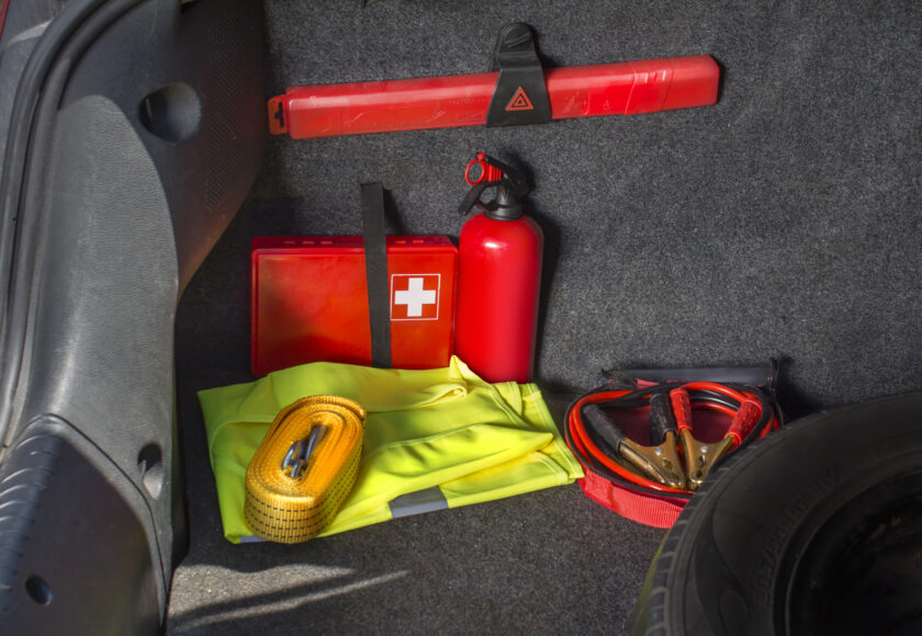 Différents équipements automobiles stockés dans une voiture avec notamment un extincteur, une trousse de premiers secours, un gilet de sécurité, un triangle de pré signalisation, etc...