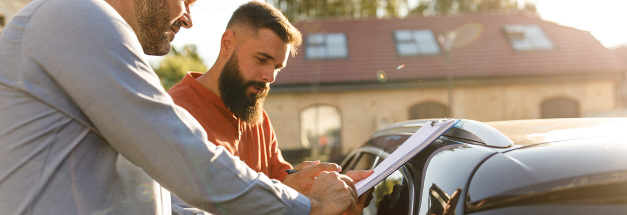 Deux hommes en train de faire un tour de vérification du véhicule pour certainement valider une vente de véhicule entre particulier.