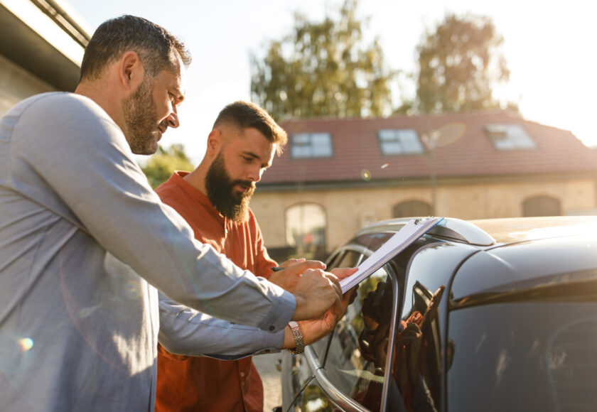 Deux hommes en train de faire un tour de vérification du véhicule pour certainement valider une vente de véhicule entre particulier.